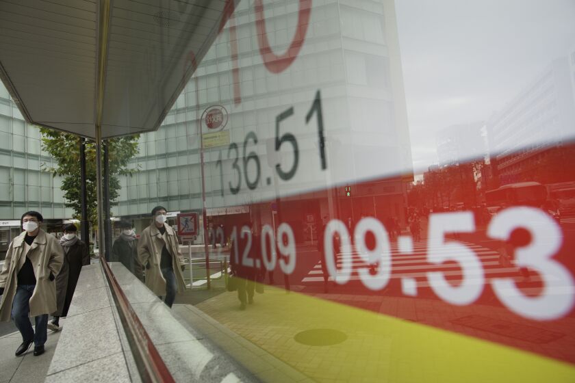 People walk by monitors showing an exchange rate of the Japanese yen against the U.S. dollar at a securities firm in Tokyo, Friday, Dec. 9, 2022. (AP Photo/Hiro Komae)