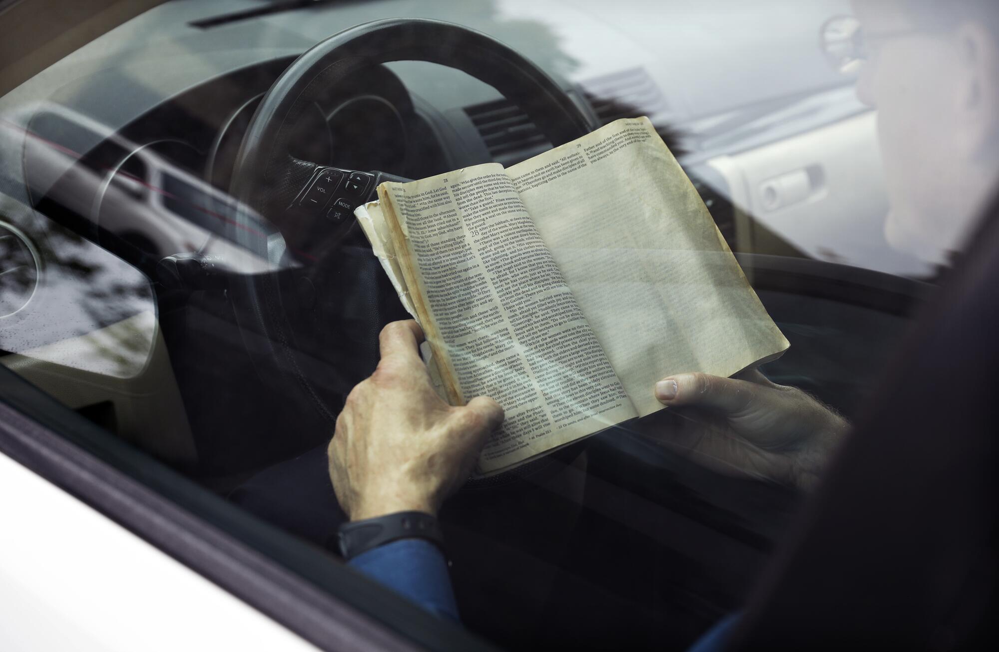 A man follows along with his bible as fellow worshippers gathering in their cars in a parking lot in Santa Ana to worship in an Easter service by Rev. Robert A. Schuller on Easter Sunday.