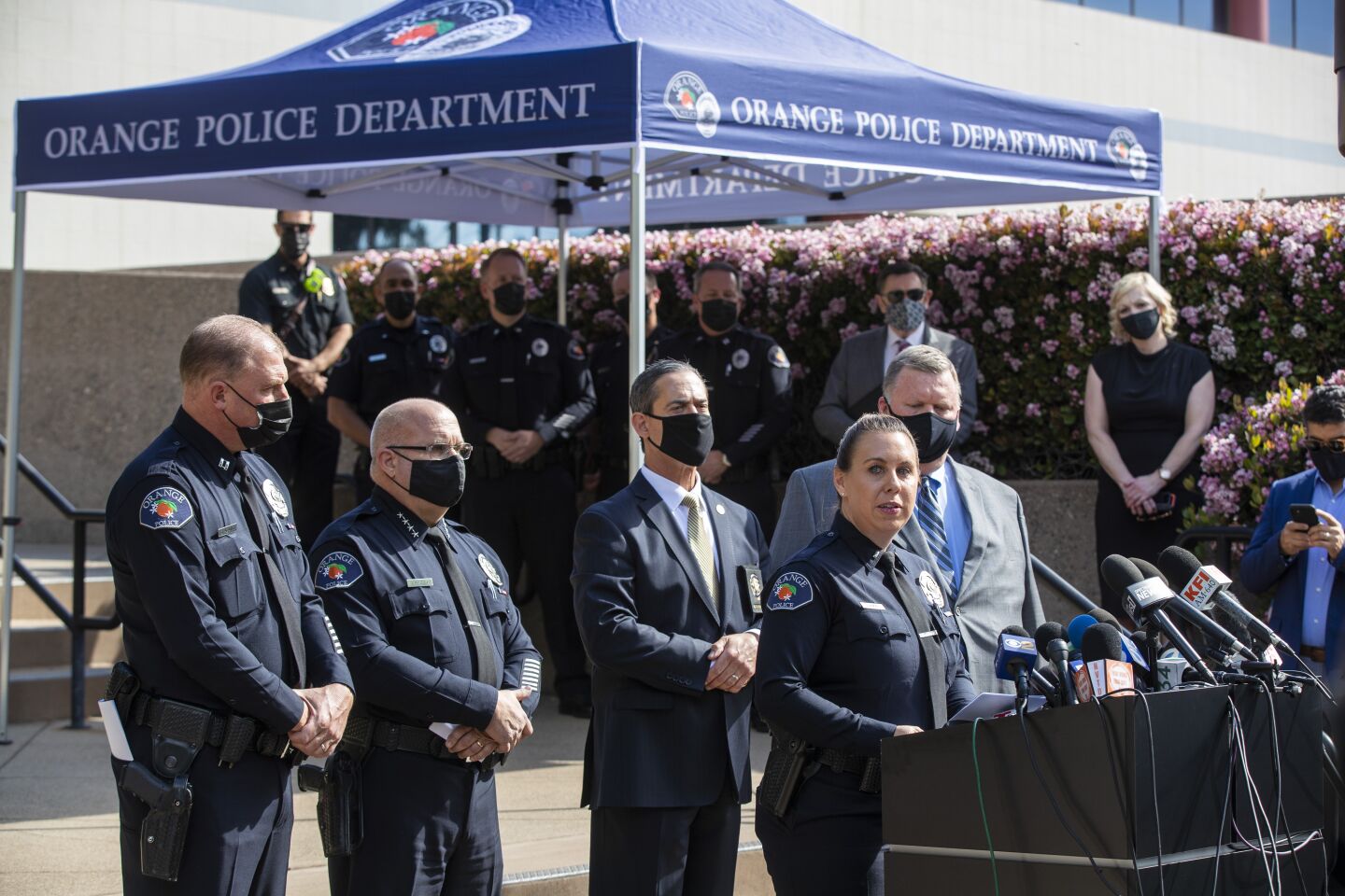 Jennifer Amat, with officers and detectives, speaks at a news conference.