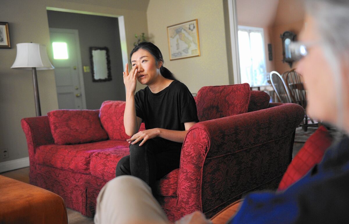 Binna Kim, the lone survivor of a murder-suicide by her father a decade ago, becomes emotional while visiting with her eighth-grade English teacher, Annie Costanzo.