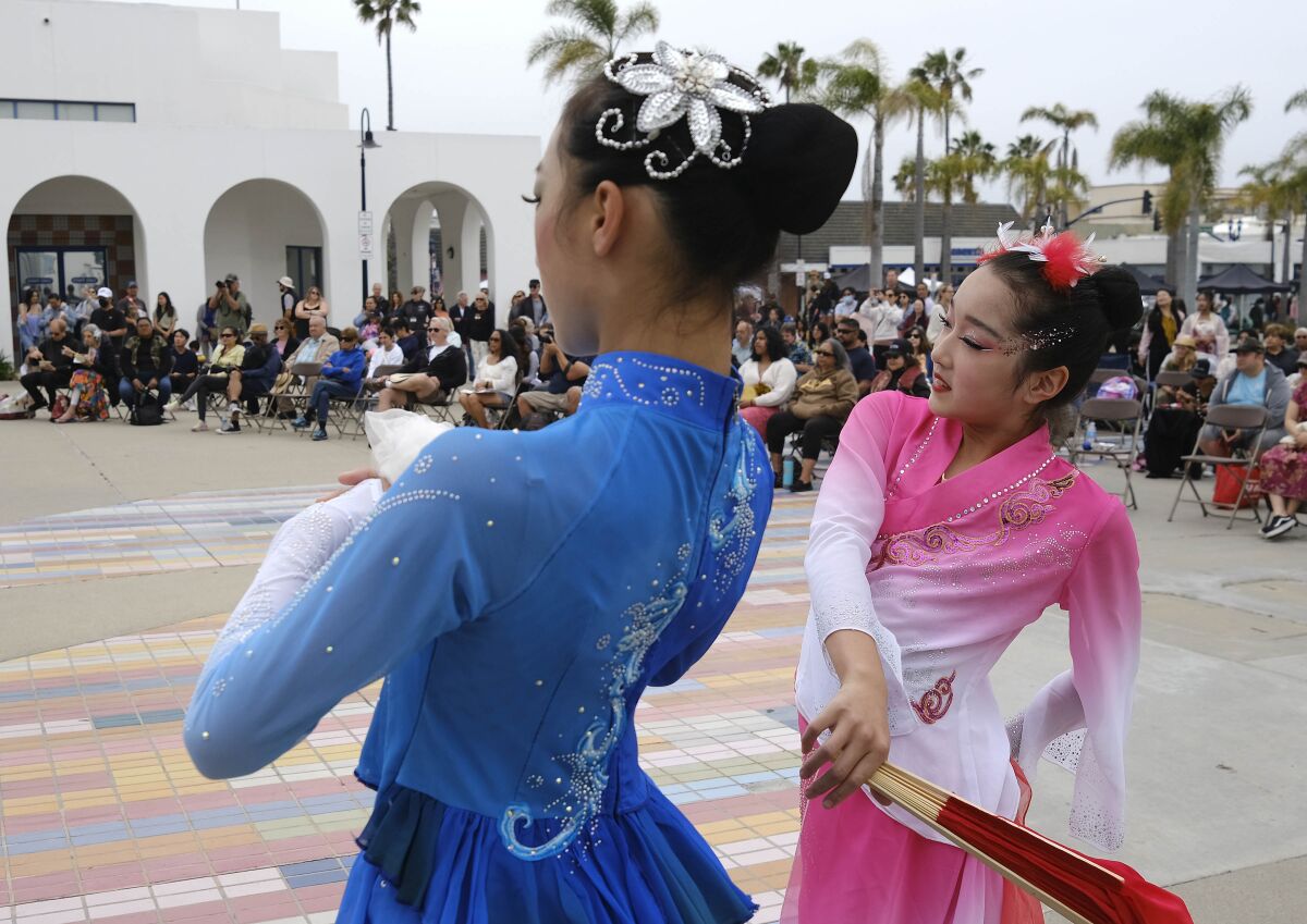 Maggie Chen, left, and Isabelle Qiao, both 12, stretch before performing with the XingJian Dance Studio in Oceanside