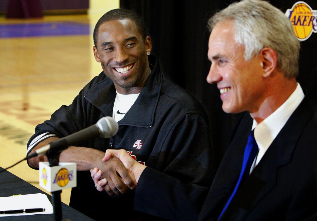 Kobe Bryant shakes hands with Lakers General Manager Mitch Kupchack after the star guard re–signed with the team on July 15, 2004.