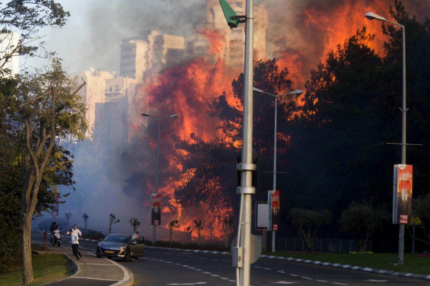 People run as wildfires rages in Haifa, Israel, Thursday, Nov. 24, 2016.