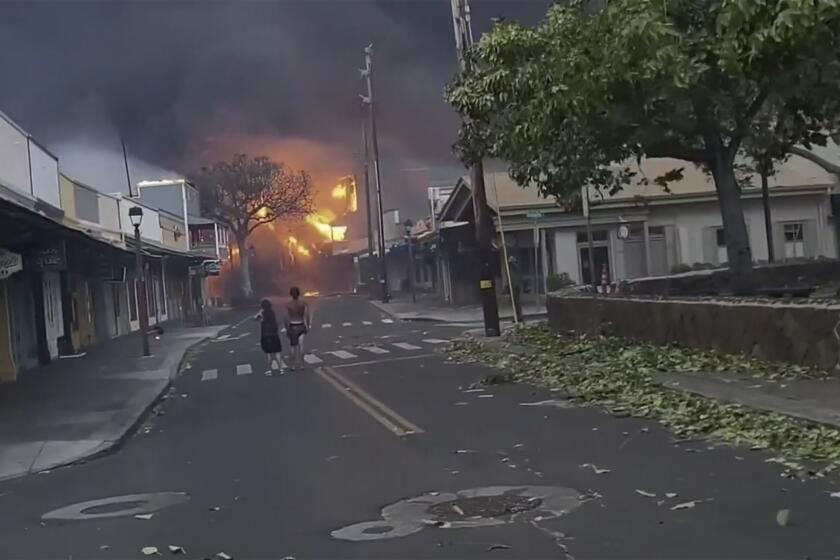 CORRECTS DATE TO AUG. 8 - People watch as smoke and flames fill the air from raging wildfires on Front Street in downtown Lahaina, Maui on Tuesday, Aug. 8, 2023. Maui officials say wildfire in the historic town has burned parts of one of the most popular tourist areas in Hawaii. County of Maui spokesperson Mahina Martin said in a phone interview early Wednesday says fire was widespread in Lahaina, including Front Street, an area of the town popular with tourists. (Alan Dickar via AP)