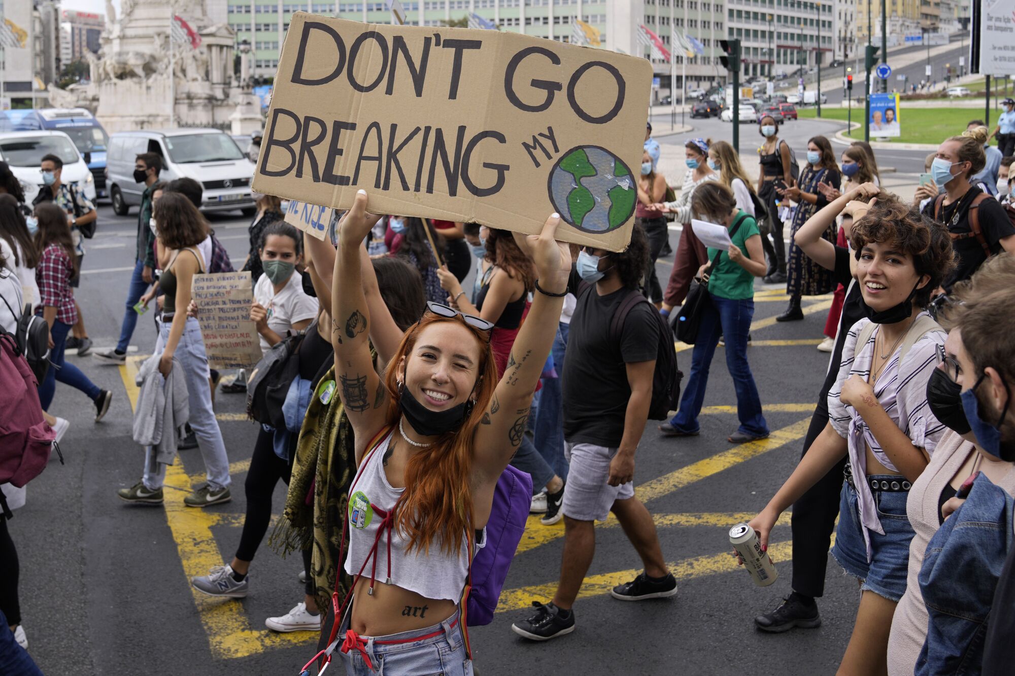 A young woman holds a sign that reads, "Don't go breaking my planet."
