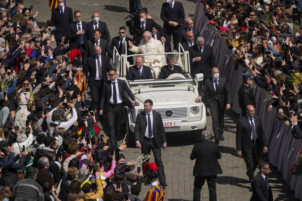 Pope Francis greets the faithful as he leaves after celebrating Palm Sunday Mass in St. Peter's Square at the Vatican, Sunday, April 10, 2022. The Roman Catholic Church enters Holy Week, retracing the story of the crucifixion of Jesus and his resurrection three days later on Easter Sunday. (AP Photo/Gregorio Borgia)