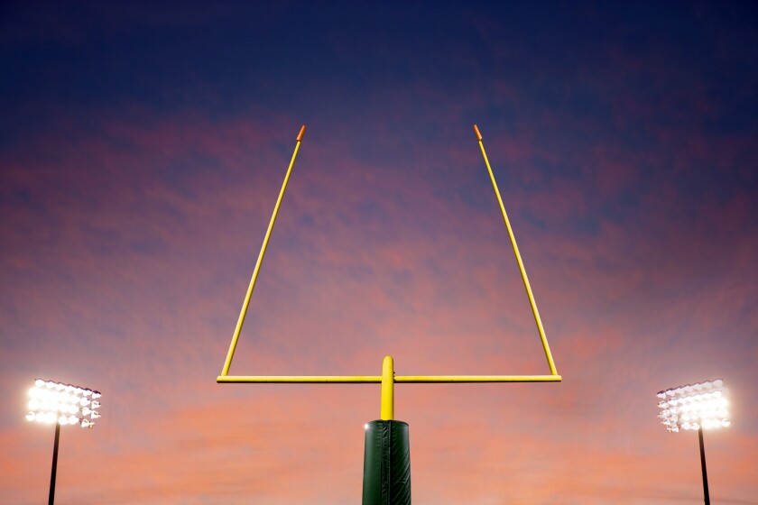Football goalpost with lit field lights at sunset 