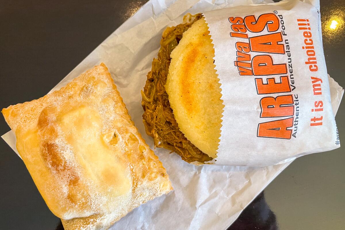 An arepa in a paper wrapper at Viva Las Arepas.