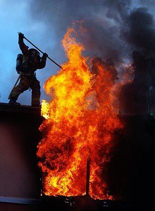 A firefighter confronts flames roaring from a second-story window of a Boyle Heights apartment complex Monday morning. The fire caused more than $250,000 in damage and forced a family of eight out of its home.