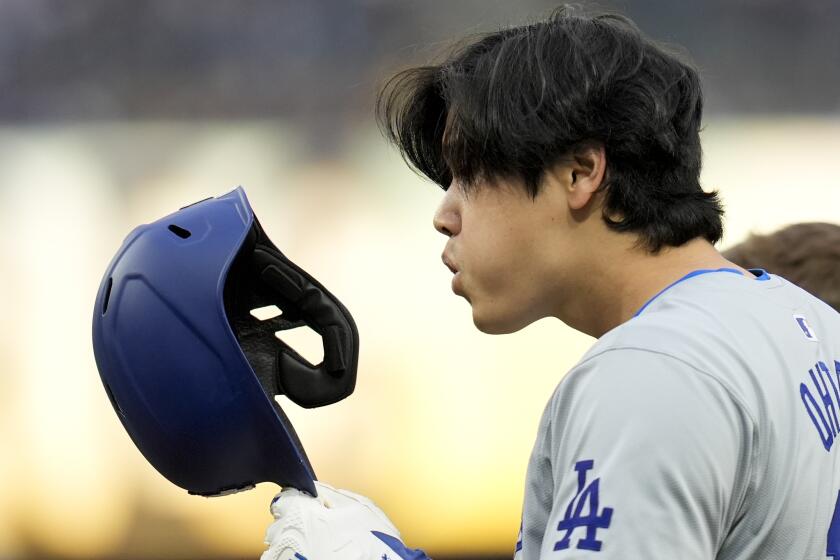 Los Angeles Dodgers' Shohei Ohtani blows dirt out of his helmet as he stands on first base after a walk during the sixth inning of a baseball game against the San Diego Padres, Saturday, May 11, 2024, in San Diego. (AP Photo/Gregory Bull)