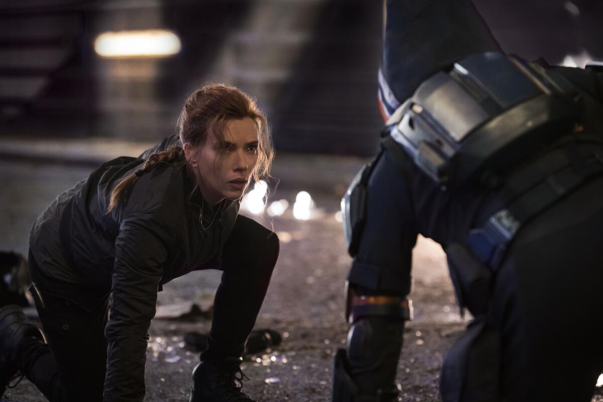 Black Widow/Natasha Romanoff (Scarlett Johansson) kneels on a street facing a hooded figure