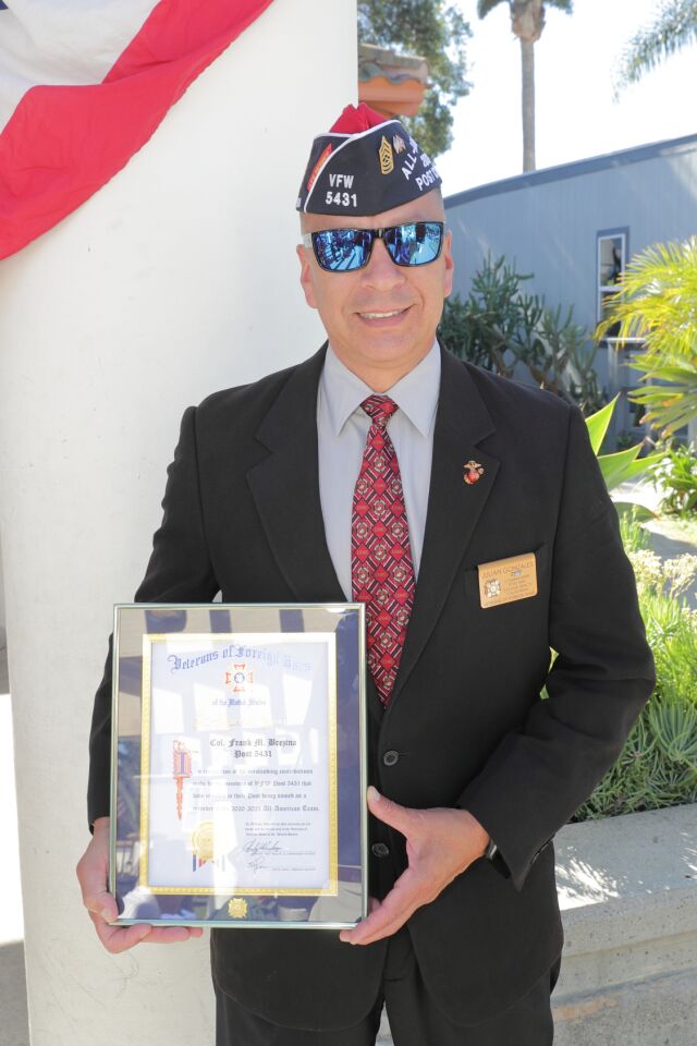 VFW Post Commander Julian Gonzales holds a plaque from the VFW that recognizes Post 5431 as an All-American Post