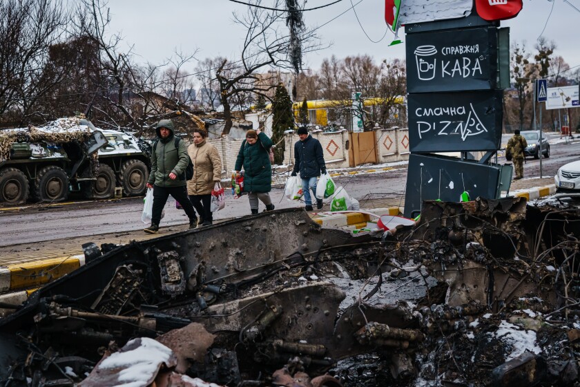 Residents carrying supplies walk back from the direction of Bucha, amid the debris of battle with Russian forces in Irpin