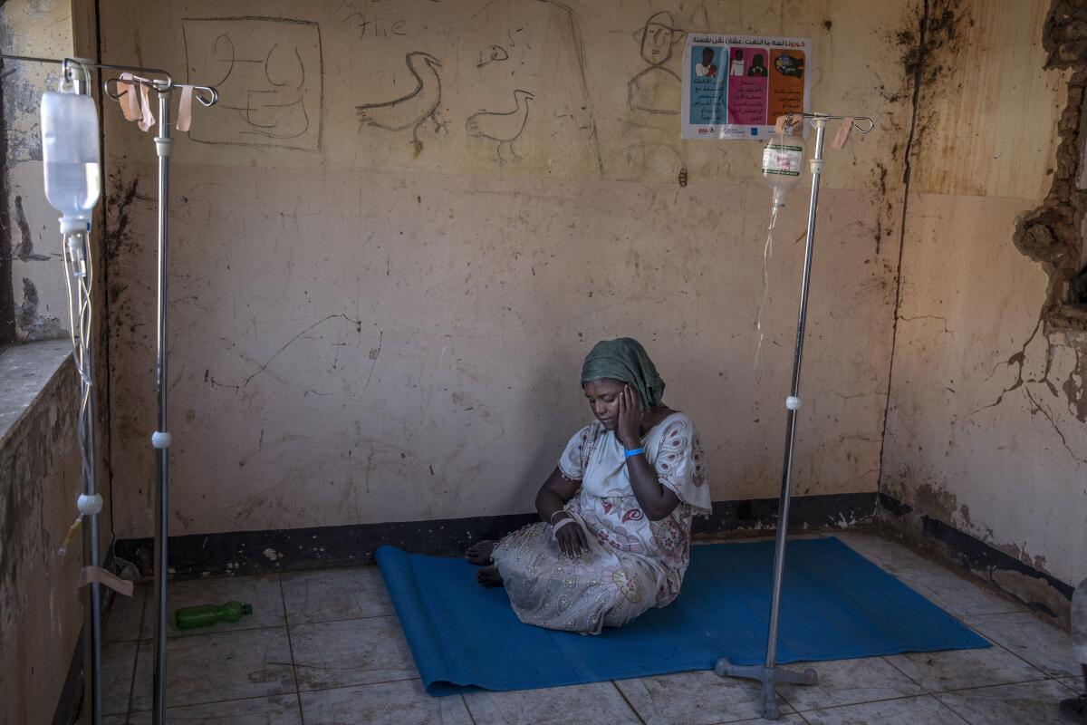 FILE - In this Nov. 25, 2020, file photo, a woman who fled the conflict in Ethiopia's Tigray region waits to get treatment at a clinic in Umm Rakouba refugee camp in Qadarif, eastern Sudan. In a remote part of neighboring Sudan, no coronavirus testing is taking place in the crowded camps that are now home to more than 45,000 Ethiopian refugees. People share shelters and stand close together in lines for food, cash and registration. There are few face masks to be seen. (AP Photo/Nariman El-Mofty, File)