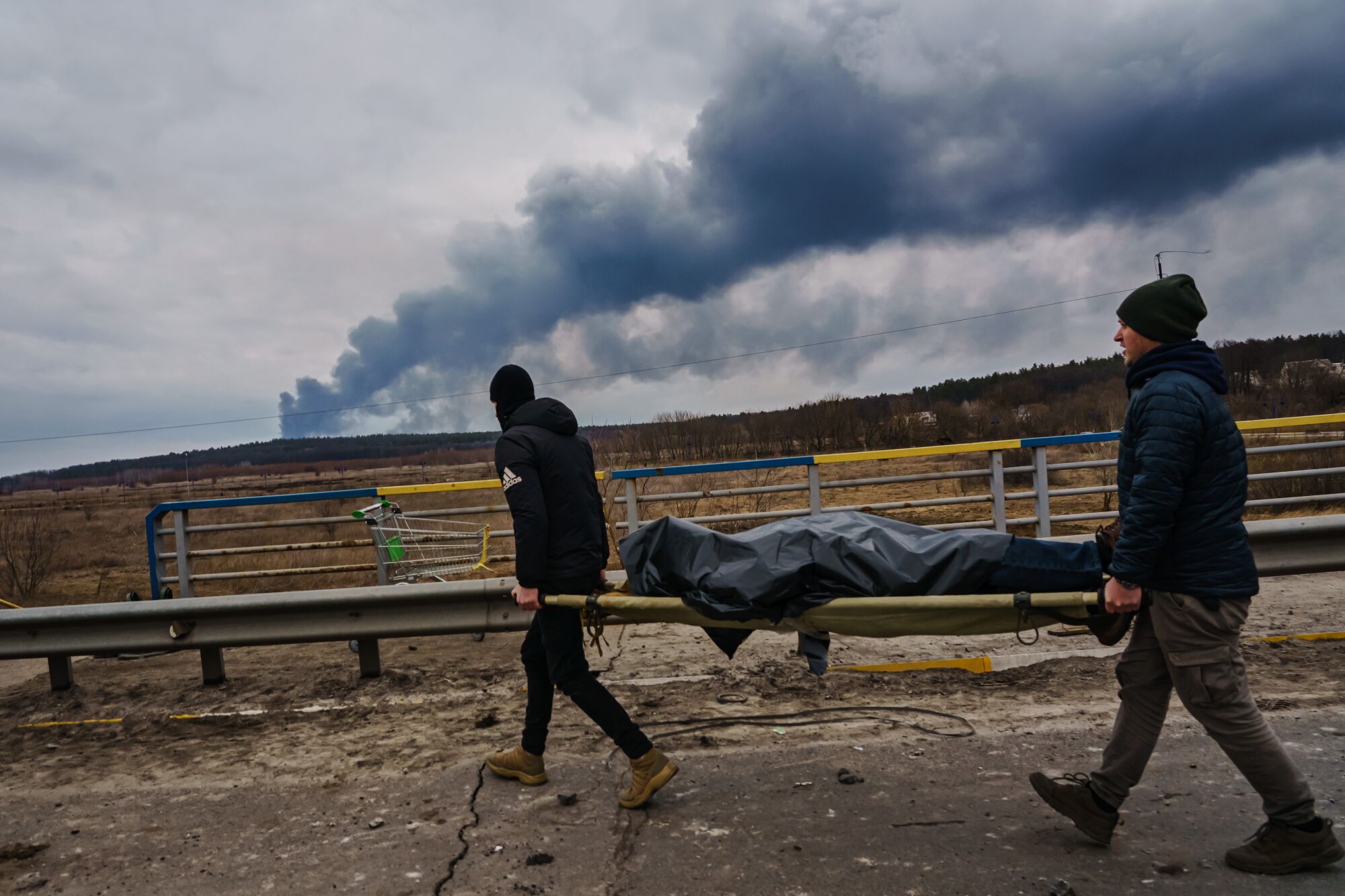 Ukrainian volunteers help remove a dead civilian body in Urpin.
