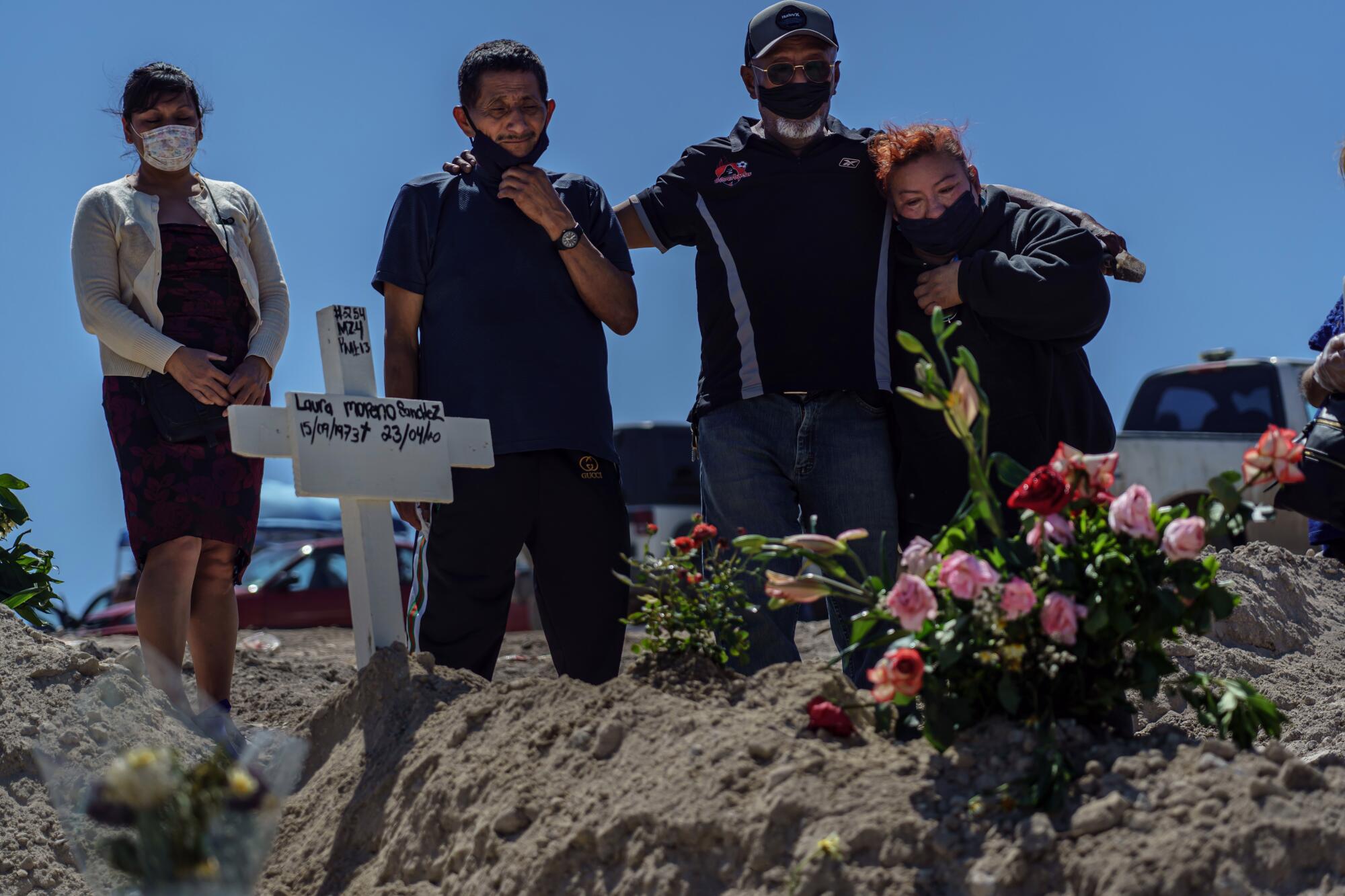 From left, Bernadina Cruz Perez, Fredy Villa Suerte Hernandez, Dominguez Hernandez, and Cleotilde Hernandez mourn the death of Laura Moreno Sanchez, 49, Fredy's wife who passed away from COVID-19, at the municipal pantheon number 13 cemetery in Tijuana, Mexico, on April 25, 2020. Fredy Villa Suerte Hernandez said that he does not know for a fact that if he is actually burying the body of his wife. He claimed that authorities did not let him open the casket. She died after being hospitalized at the Tijuana General Hospital for 11 days for COVID-19. "I don't know if it is my wife or not. I did not see the body."