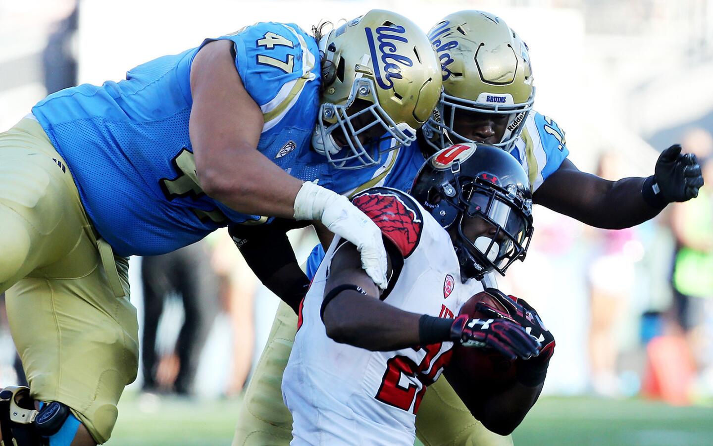 UCLA defenders Eddie Vanderdoes, left, and Jayon Brown bring down Utah running back Joe Williams after a gain in the fourth quarter.