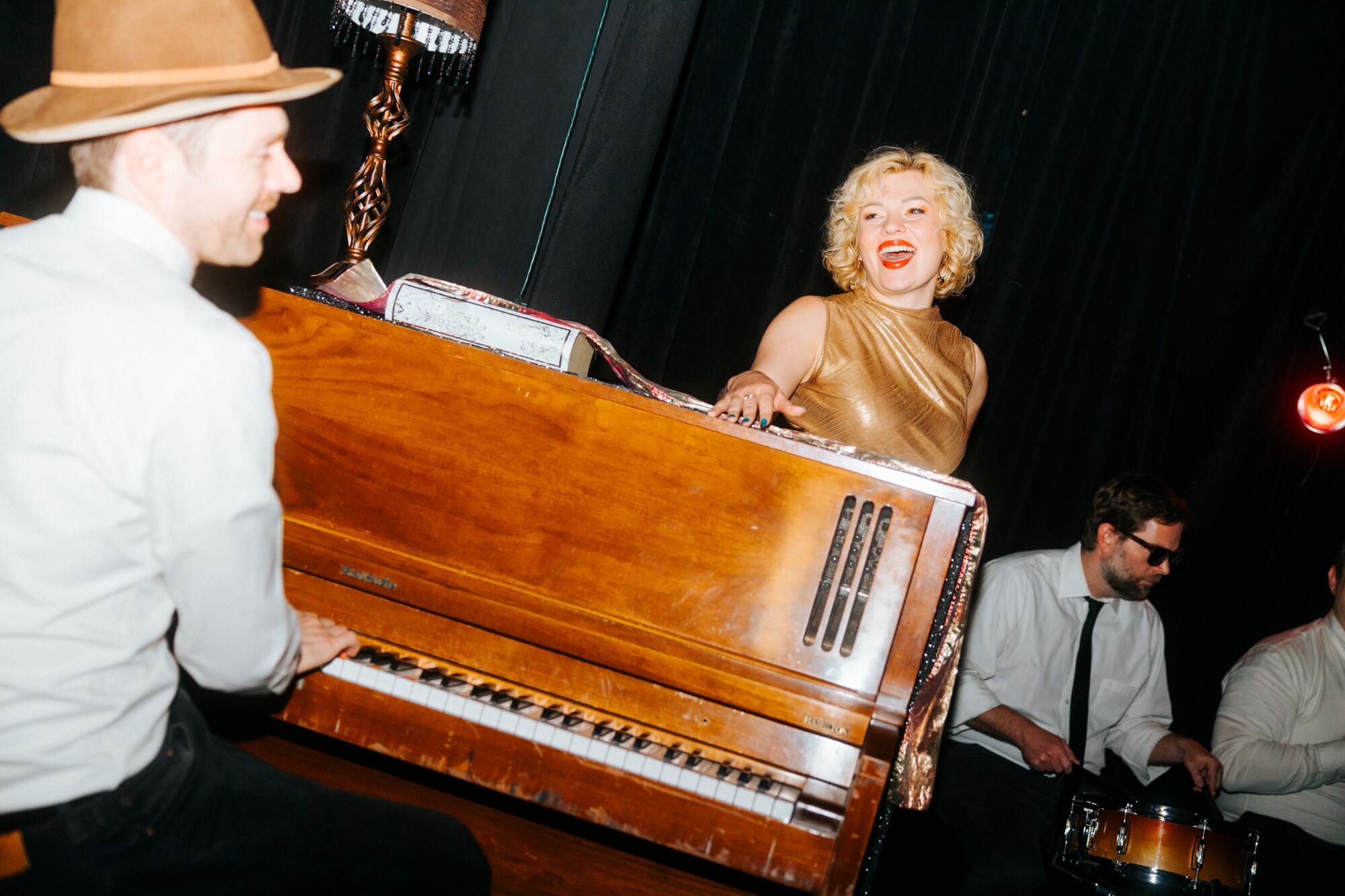 A pistillate sings propped up connected a standup piano.
