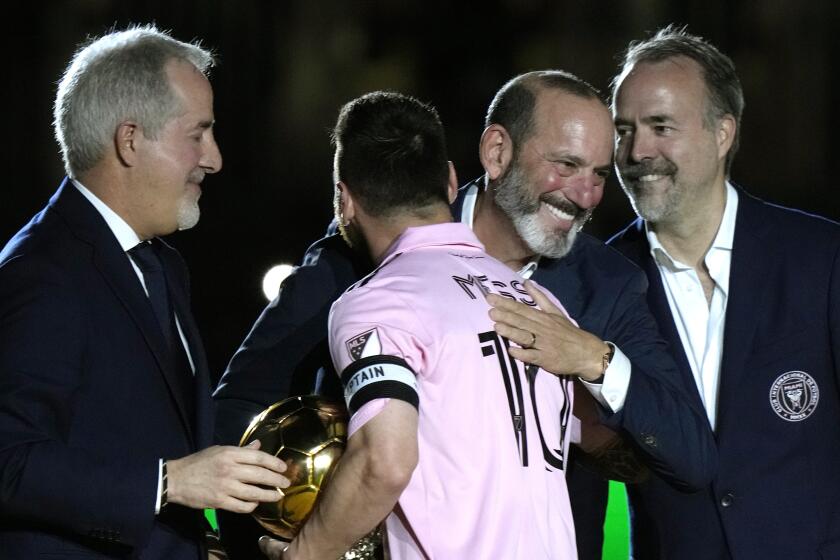Inter Miami forward Lionel Messi is hugged by MLS Commissioner Don Garber, center right.