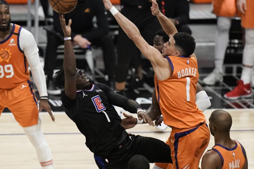 Los Angeles Clippers' Reggie Jackson, center left, is defended by Phoenix Suns' Devin Booker.