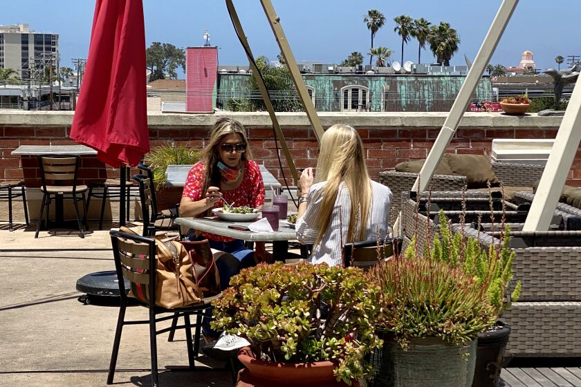 Customers eat at Trilogy Sanctuary's newly reopened rooftop cafe May 22 in La Jolla. Tables are spaced 10 feet apart for social distancing.