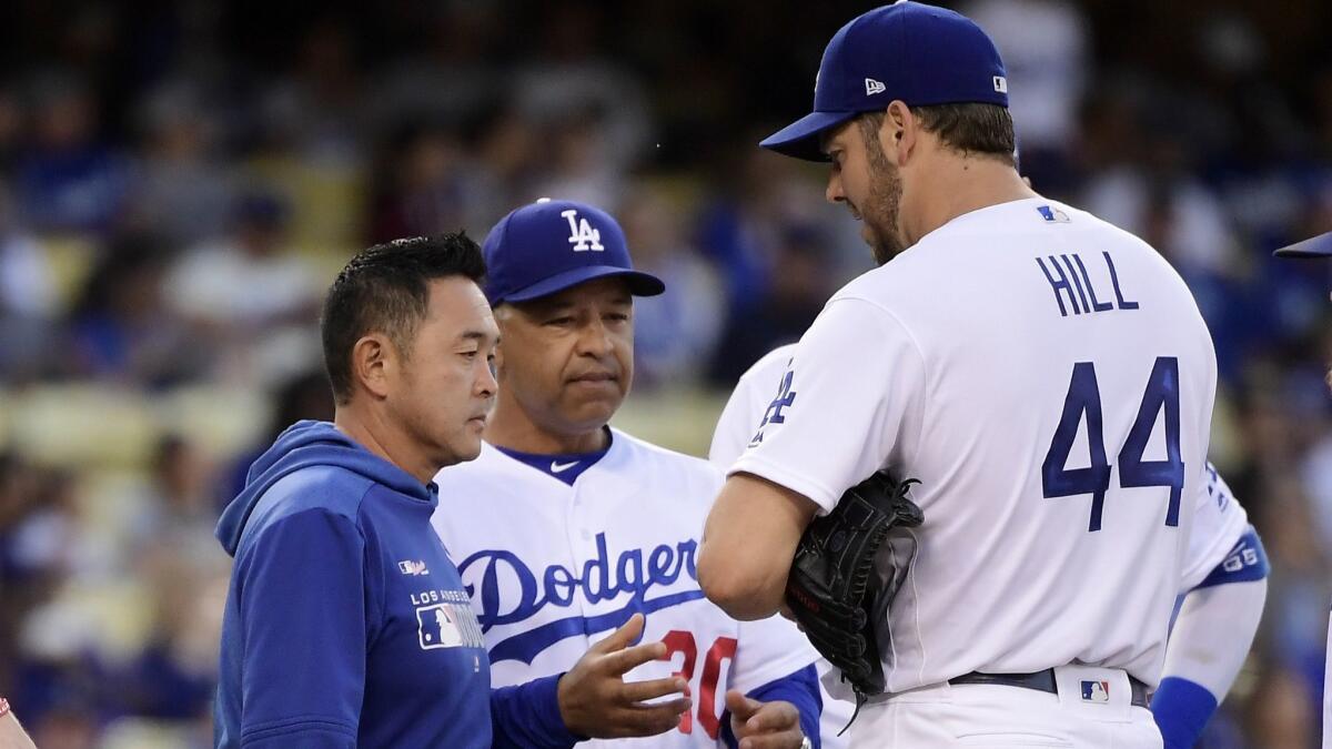 Dodgers pitcher Rich Hill, right, is taken out of the game by manager Dave Roberts, center, due to an injury prior to the second inning against the San Francisco Giants on Wednesday at Dodger Stadium.