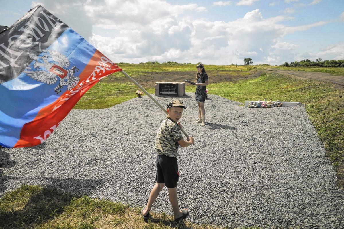 A boy waves a flag of the self-proclaimed Donetsk People's Republic on July 16 at a memorial to the victims of the downedMalaysian Airlines at the crash site near the village of Hrabove, eastern Ukraine.