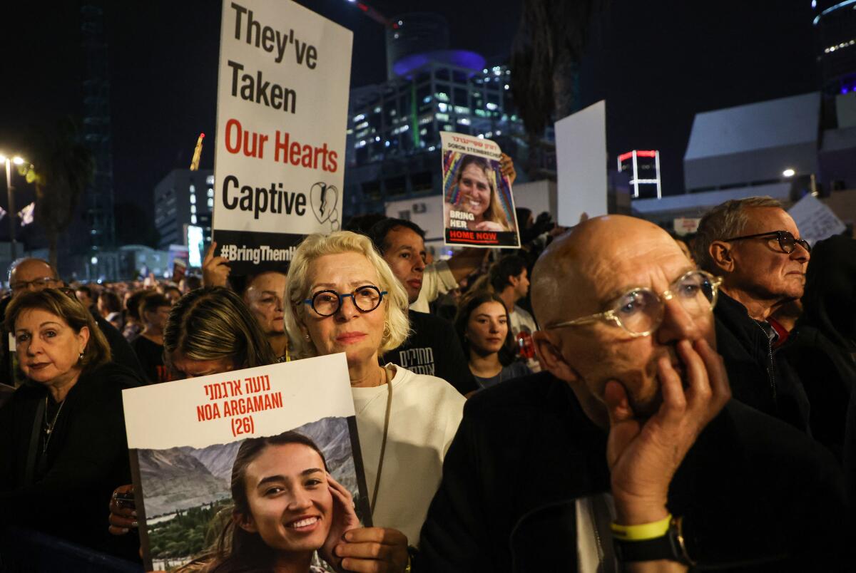 Protesters in Tel Aviv hold signs and images of hostages.