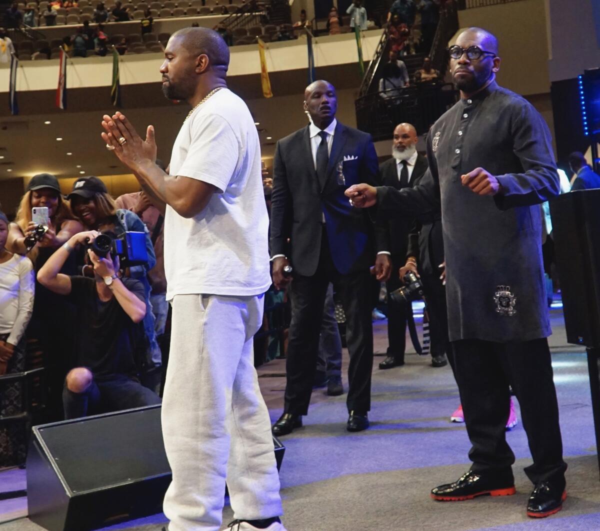 Kanye West clasping his hands in prayer among a crowd of churchgoers