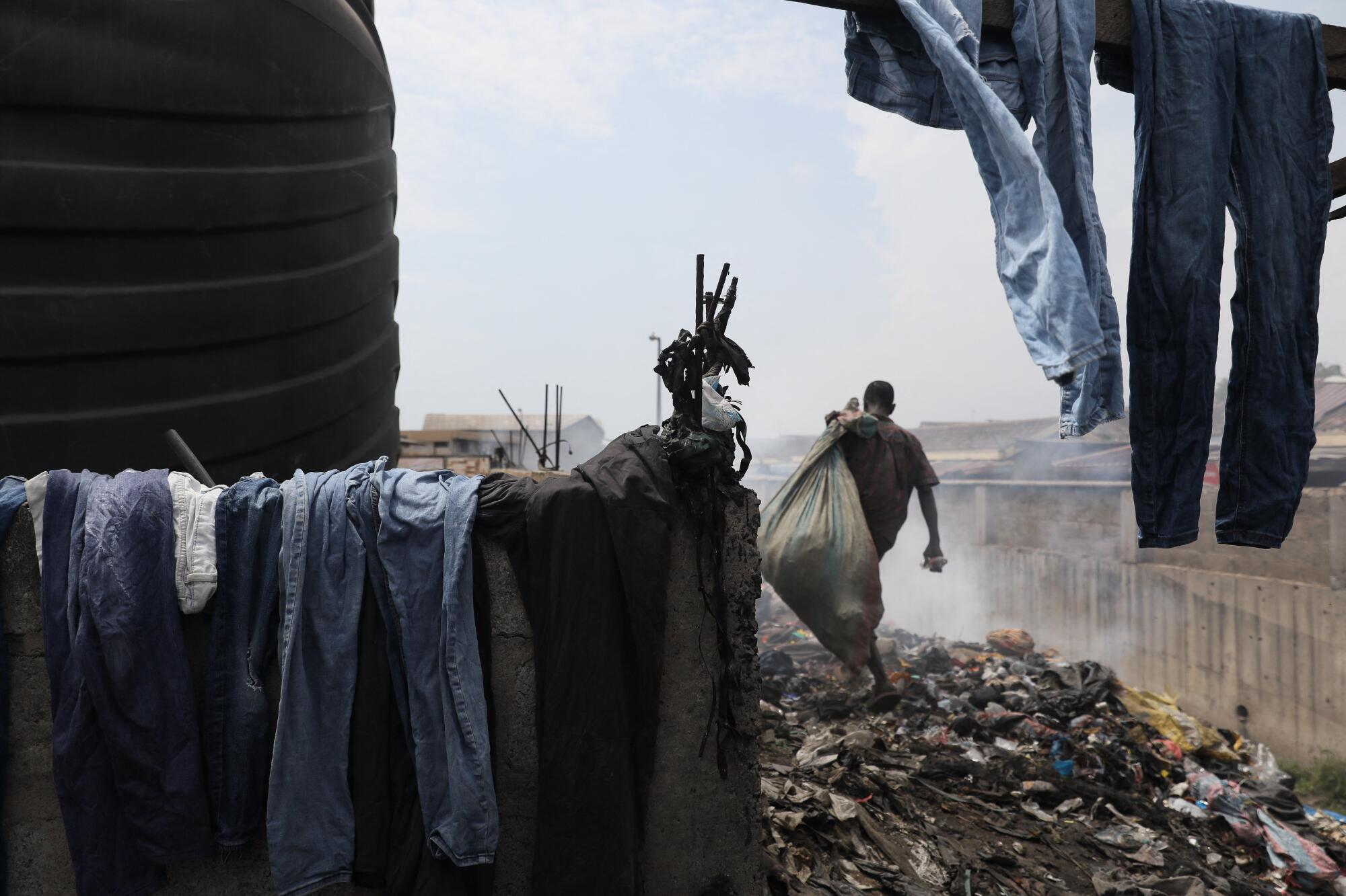 A man carries a bag away from a pile of clothes.