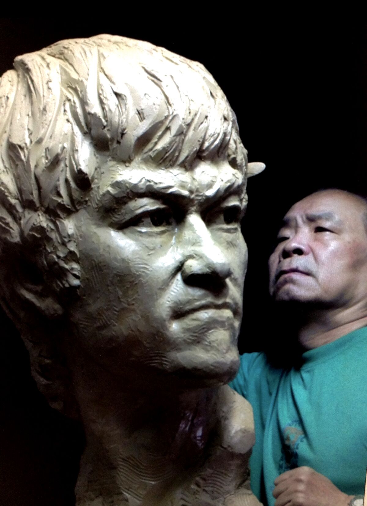 An artist crafting a sculpture of Bruce Lee.