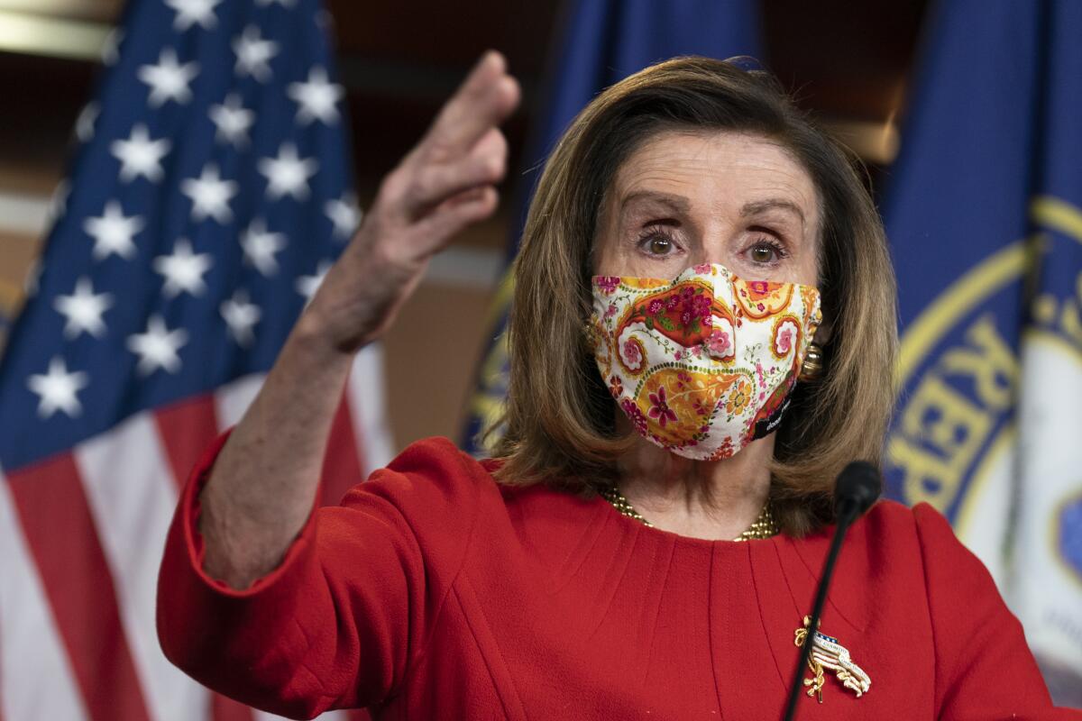 House Speaker Nancy Pelosi speaks at a lectern in a mask