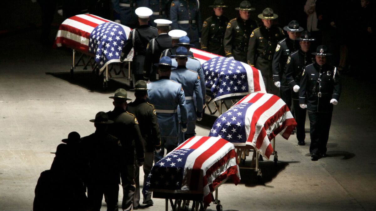 Law enforcement officers approach the caskets of four Lakewood, Wash., police officers who were gunned down in a coffee shop before the start of their shift in 2009.