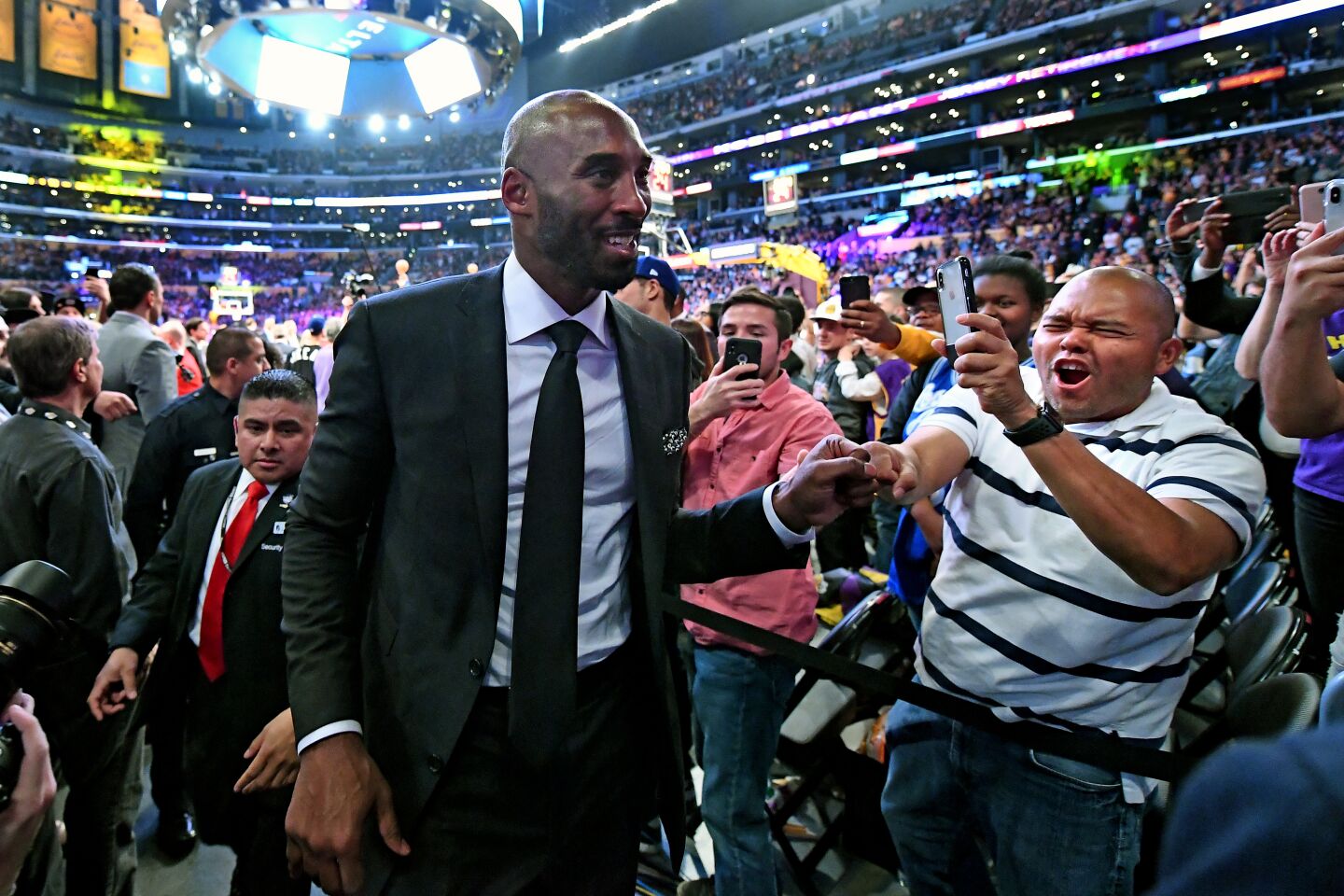 Kobe Bryant, in suit and tie, walks off the court after his jersey retirement ceremony in 2017.