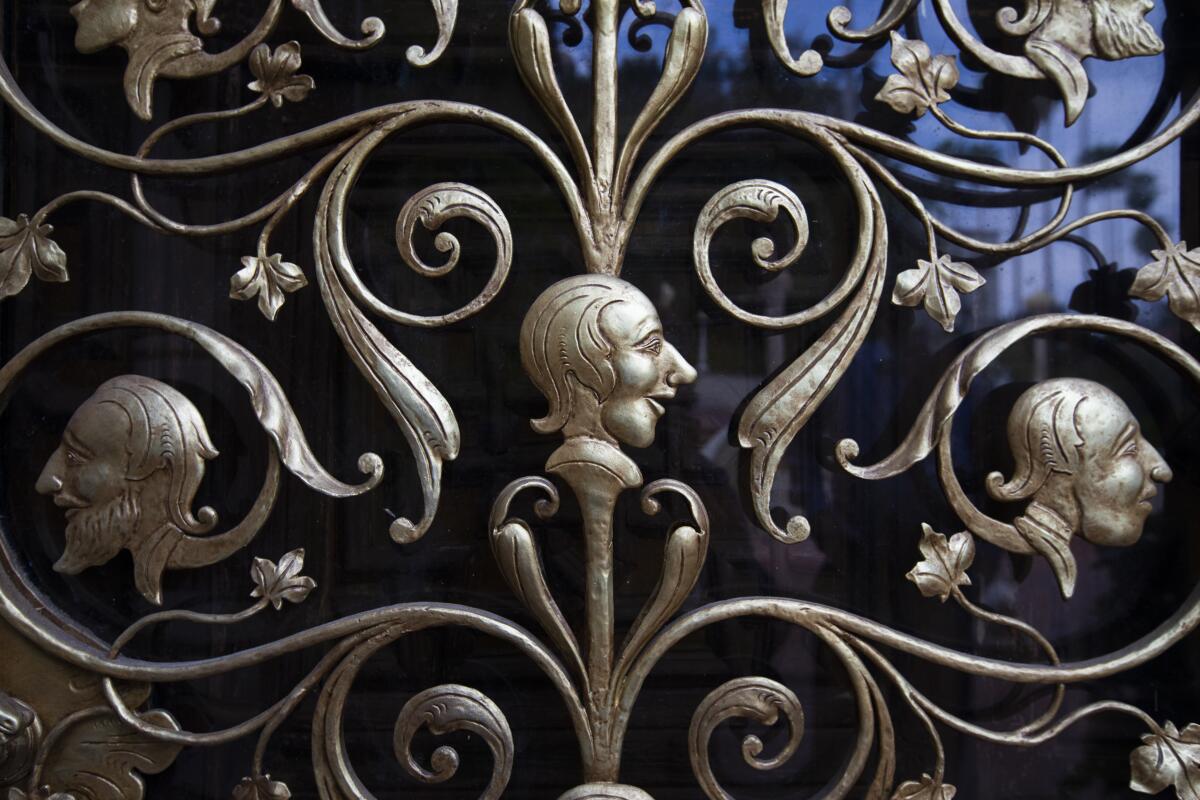 These are exterior door grilles decorated with ornamental profiled heads, made of wrought iron, painted gold.
