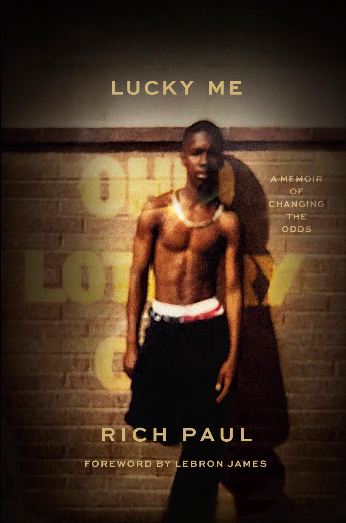 A young Rich Paul stands shirtless in front of a fence on the book jacket of his memoir "Lucky Me."