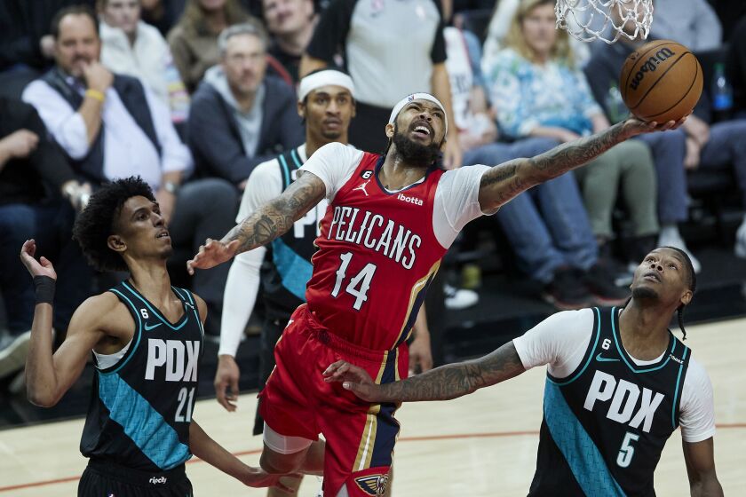 Brandon Ingram, al centro, de los Pelicans de Nueva Orleans lanza al aro entre John Butler Jr., izquierda, y Cam Reddish de los Trail Blazers de Portland, el lunes 27 de marzo de 2023, en Portland, Oregon. (AP Foto/Craig Mitchelldyer)