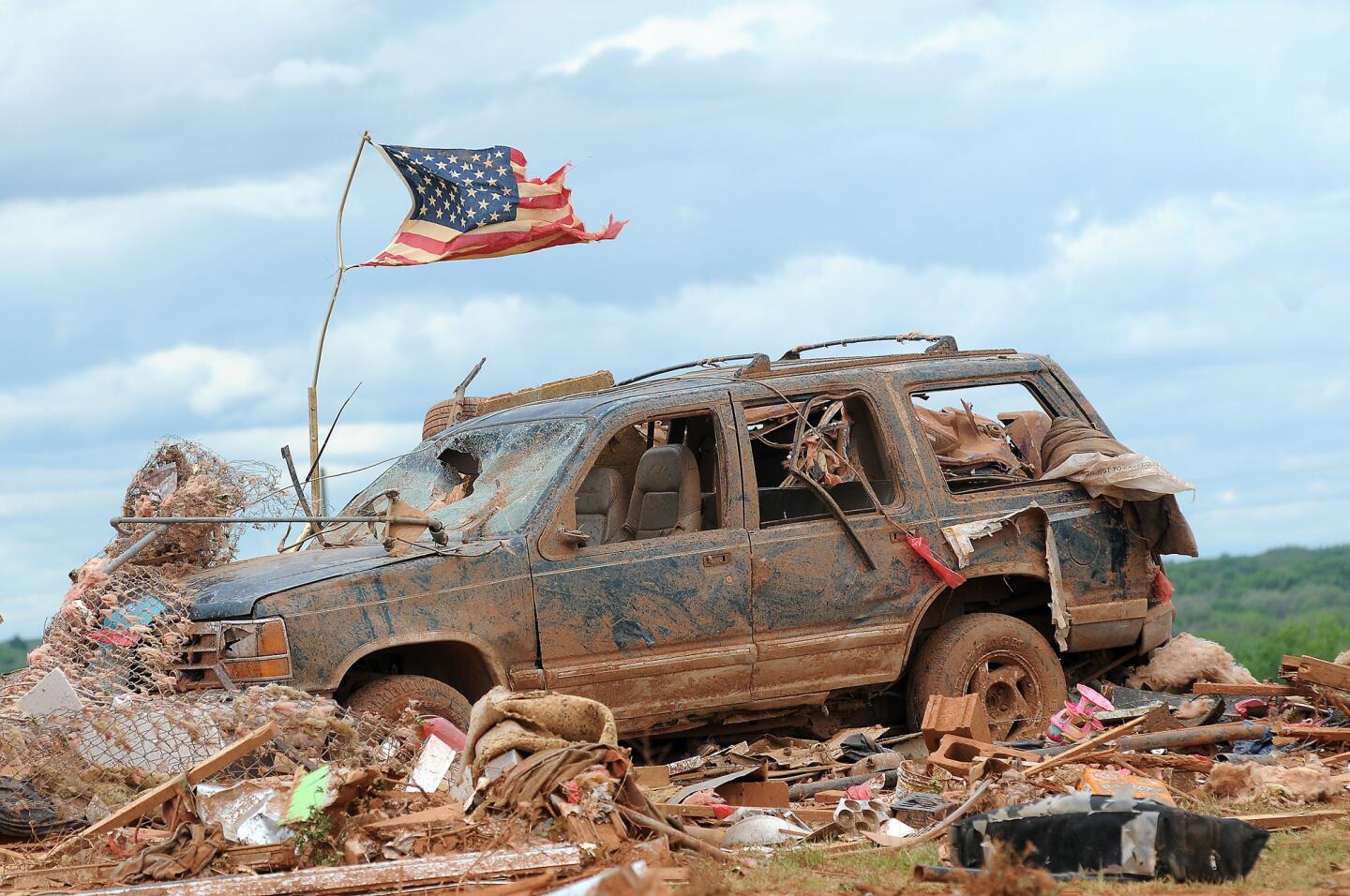 A tattered American flag flies over a vehicle where two girls, 5 and 7, were found dead after a severe thunderstorm spawned a massive tornado at Hideaway Mobile Home Villa in Woodward, Okla. Residents of several states scoured through the wreckage of battered homes and businesses Sunday, after dozens of tornadoes blitzed the Midwest and Plains Saturday, leaving six dead and 29 injured.
