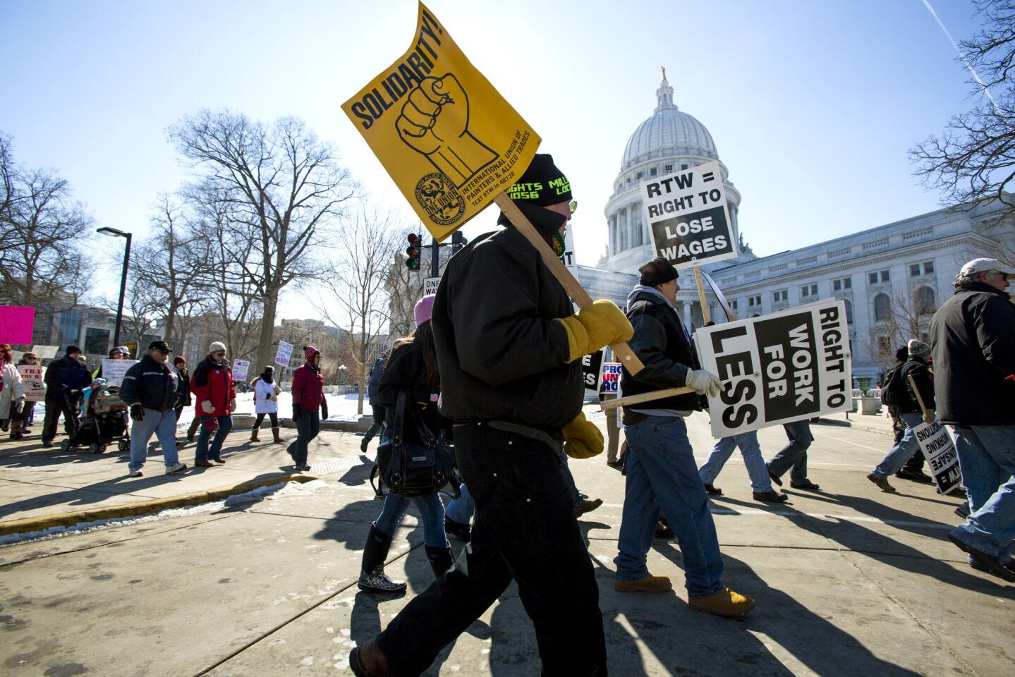 Protesters march around the Capitol after participating in a rally against a "right-to-work" proposal in Madison, Wis. Thousands of Wisconsin union workers rallied at the Capitol Saturday to protest a "right-to-work" proposal that would outlaw the mandatory payment of union dues.