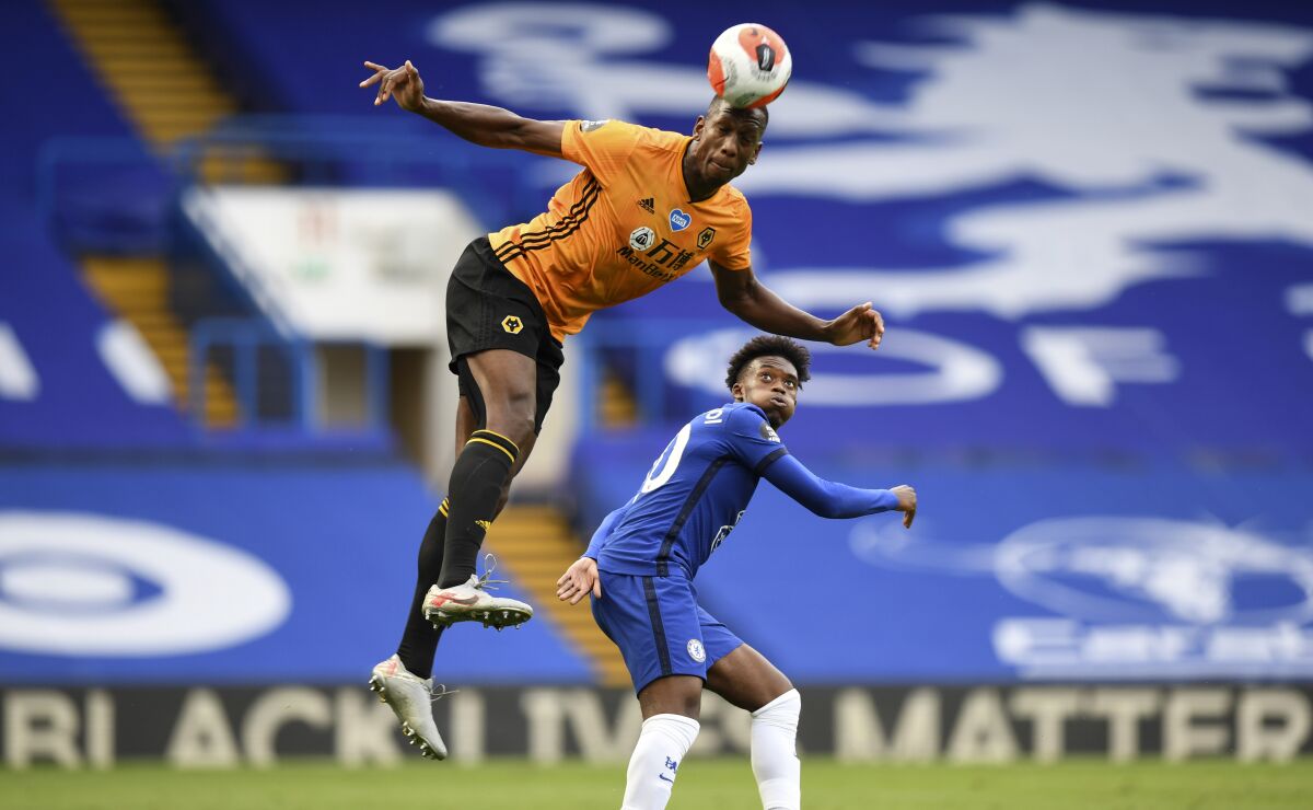 Chelsea's Willian, right, watches Wolverhampton Wanderers' Willy Boly leaping for a header during the English Premier League soccer match between Chelsea and Wolverhampton Wanderers at Stamford Bridge, in London, Sunday July 26, 2020. (Daniel Leal-Olivas/Pool via AP)