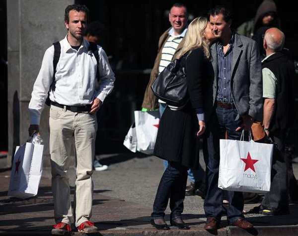 People hold their purchases outside a Macy's in New York. Americans were more cautious about spending in May while their income increased only slightly, indicating the faltering job market has stoked fears about the economy's health.