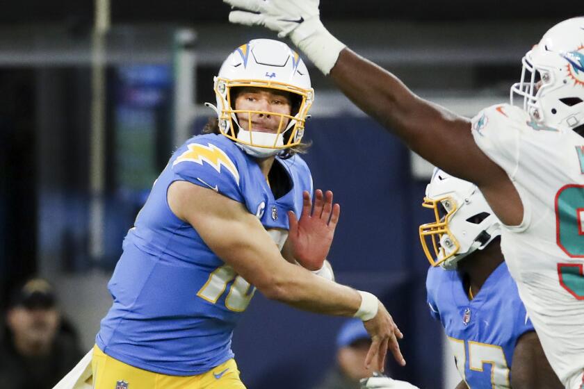 Chargers quarterback Justin Herbert throws a pass while pressured by Dolphins defensive tackle Christian Wilkins