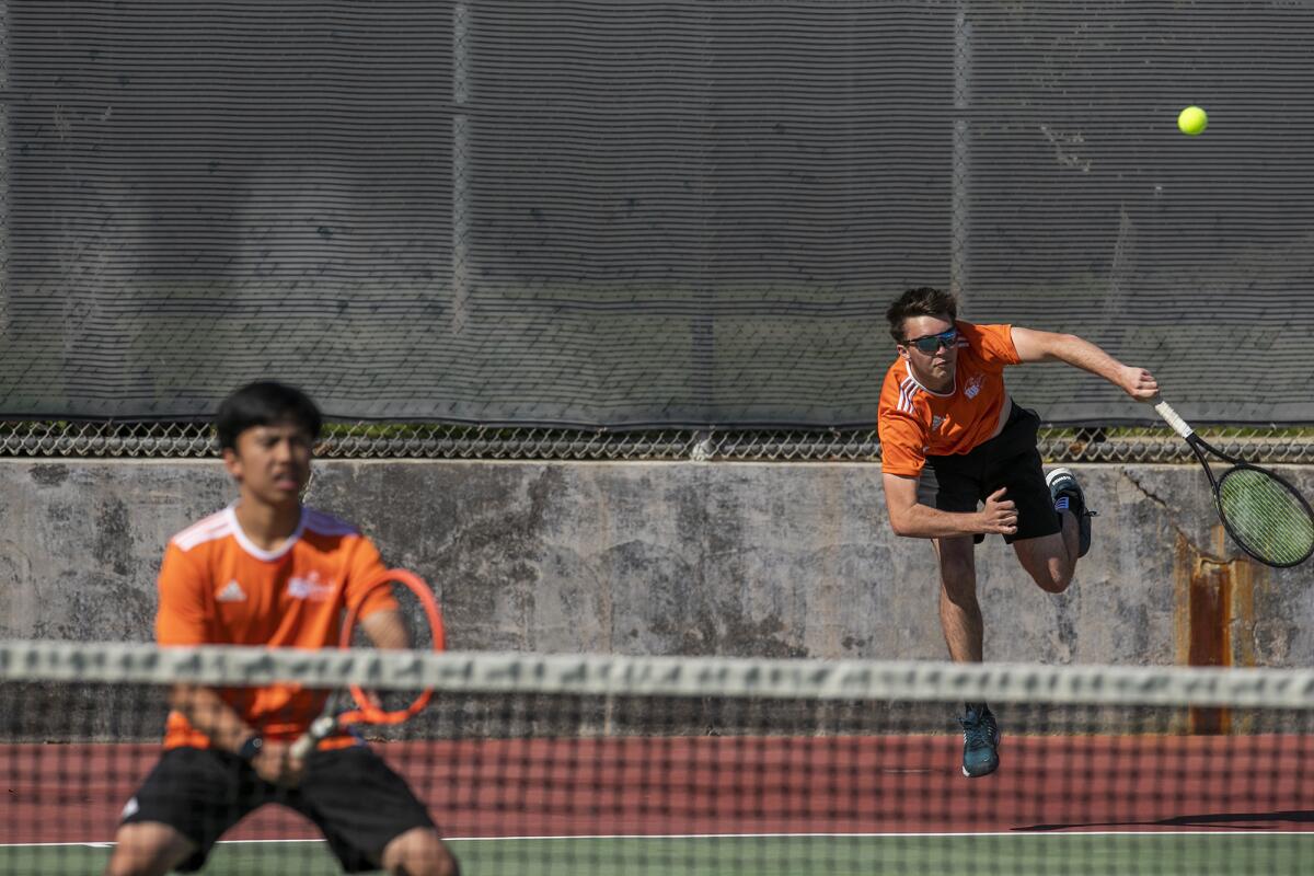 Huntington Beach's Andrew Beasley, right, serves as his partner Ethan Le waits at the net during Thursday's match.