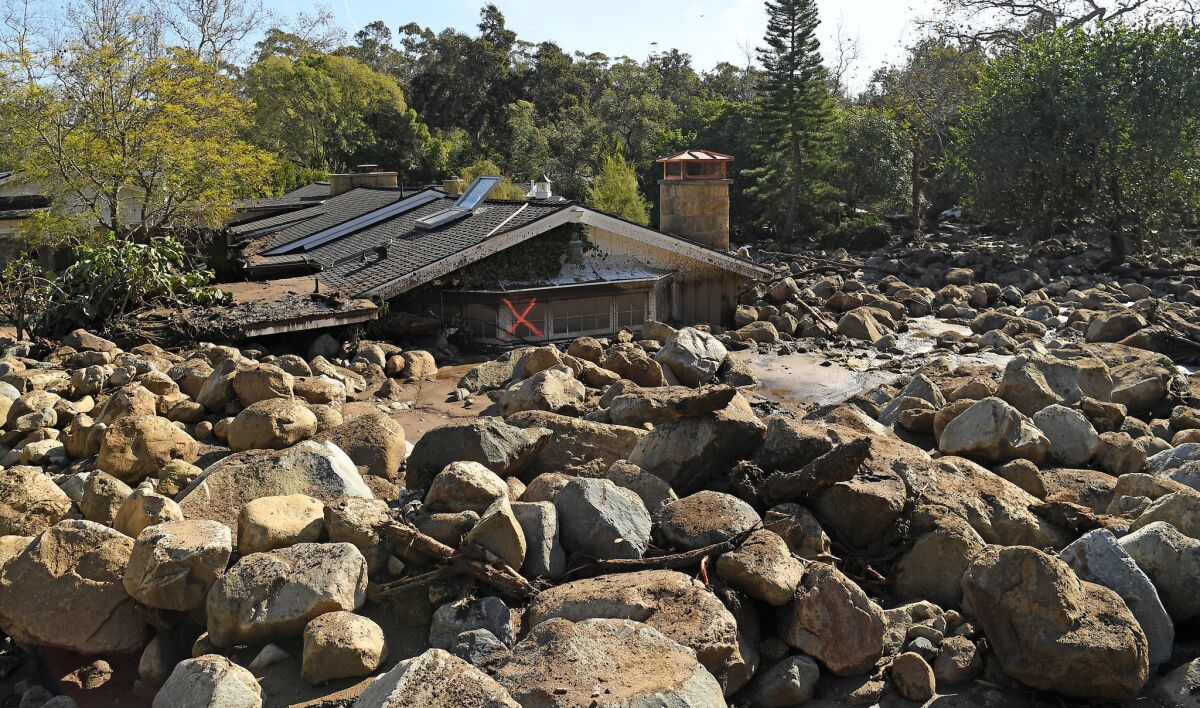 A house partially buried in boulders and mud