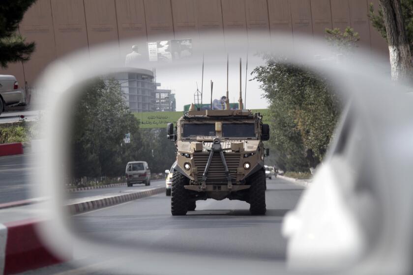 FILE - In this Aug. 23, 2017, file photo, a patrolling U.S. armored vehicle is reflected in the mirror of a car in Kabul, Afghanistan. An accelerated U.S. troop withdrawal from Afghanistan, announced by Washington, Tuesday, Nov. 17, 2020, has rattled both allies and adversaries and raised fears of worsening violence and regional chaos, which some say could embolden the Islamic State affiliate in the country to try to regroup in a lawless Afghanistan. (AP Photo/Rahmat Gul, File)