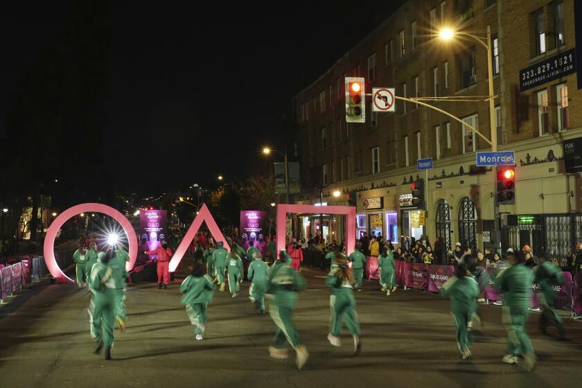 Fans run through large "Squid Game" icons outside the premiere of the second season of the Netflix series.