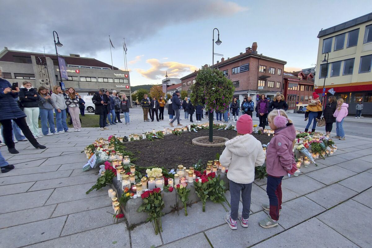 People gather around flowers and candles after a man killed several people on Wednesday afternoon, in Kongsberg, Norway, Thursday, Oct. 14, 2021. The bow-and-arrow rampage by a man who killed five people in a small town near Norway's capital appeared to be a terrorist act, authorities said Thursday, a bizarre and shocking attack in a Scandinavian country where violent crime is rare. Police identified the attacker as Espen Andersen Braathen, a 37-year-old Danish citizen, who was arrested on the street Wednesday night. (AP Photo/Pal Nordseth)