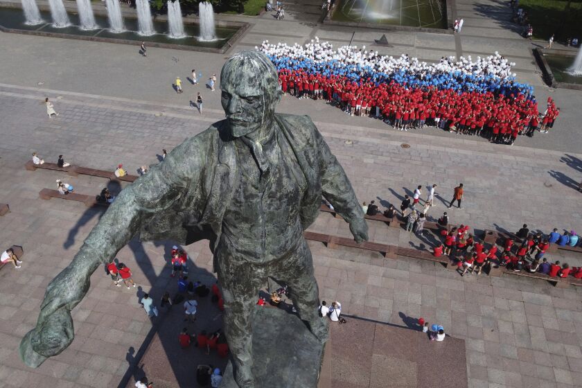 Members of pro-government youth clubs stand in the shape of the image of Russia on the map holding balloons in the colours of the Russian flag near a statue of Soviet Union founder Vladimir Lenin during preparations for the celebration of the Day of the Russian National Flag, which will be held on August 22, in St. Petersburg, Russia, Friday, Aug. 19, 2022. (AP Photo/Dmitri Lovetsky)