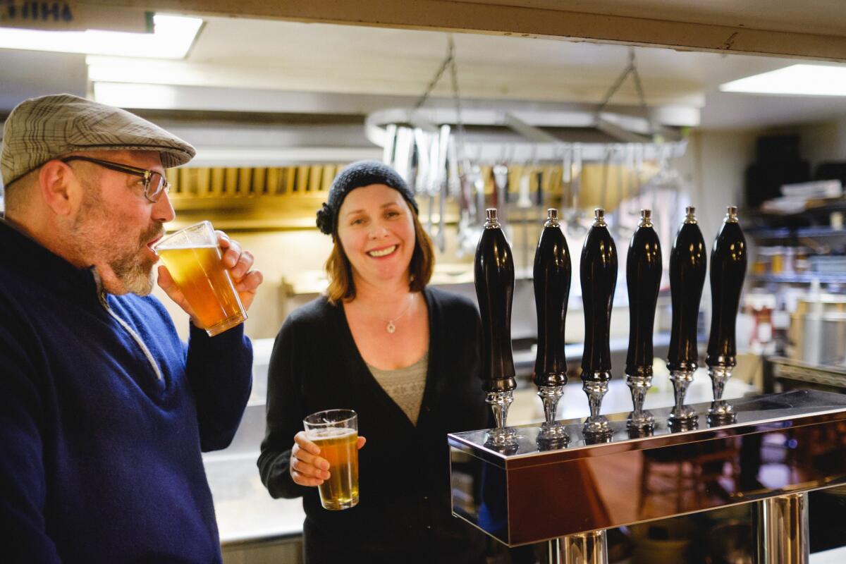 A man and a woman drink beer in a bar.
