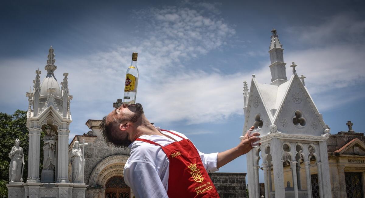 Argentine bartender Christian Delpech plays with bottles of rum at the Colon Cemetery in Havana, where one of the city's most famous bartenders is buried.